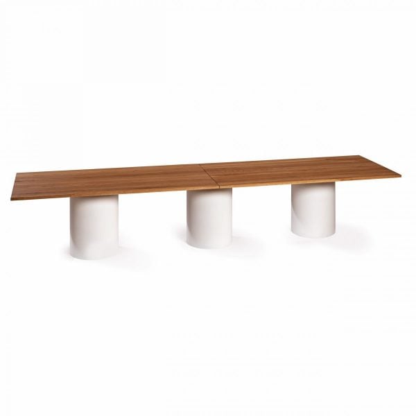 Mesa larga de comedor rectangular de madera y pies cilíndricos de hierro pintado en blanco.